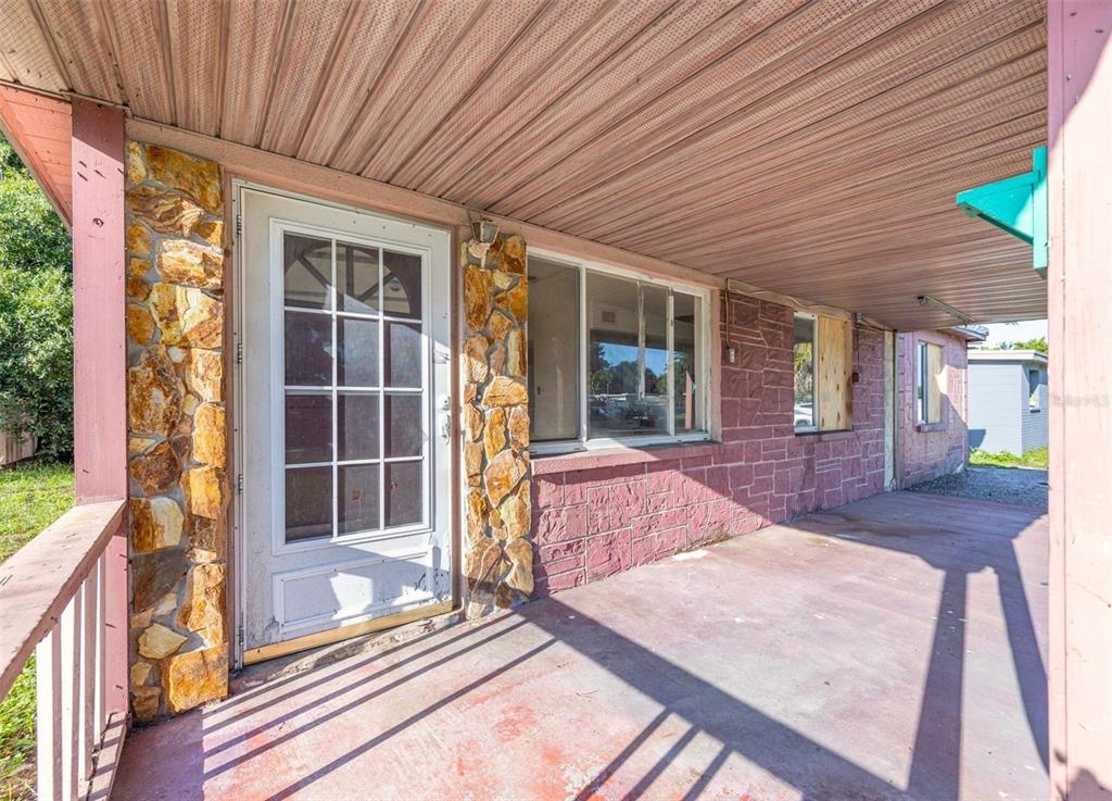 A covered porch with a stone-accented exterior wall, a glass-paneled door, and large windows — 8528 N 92ND TERRACE, SEMINOLE, FL