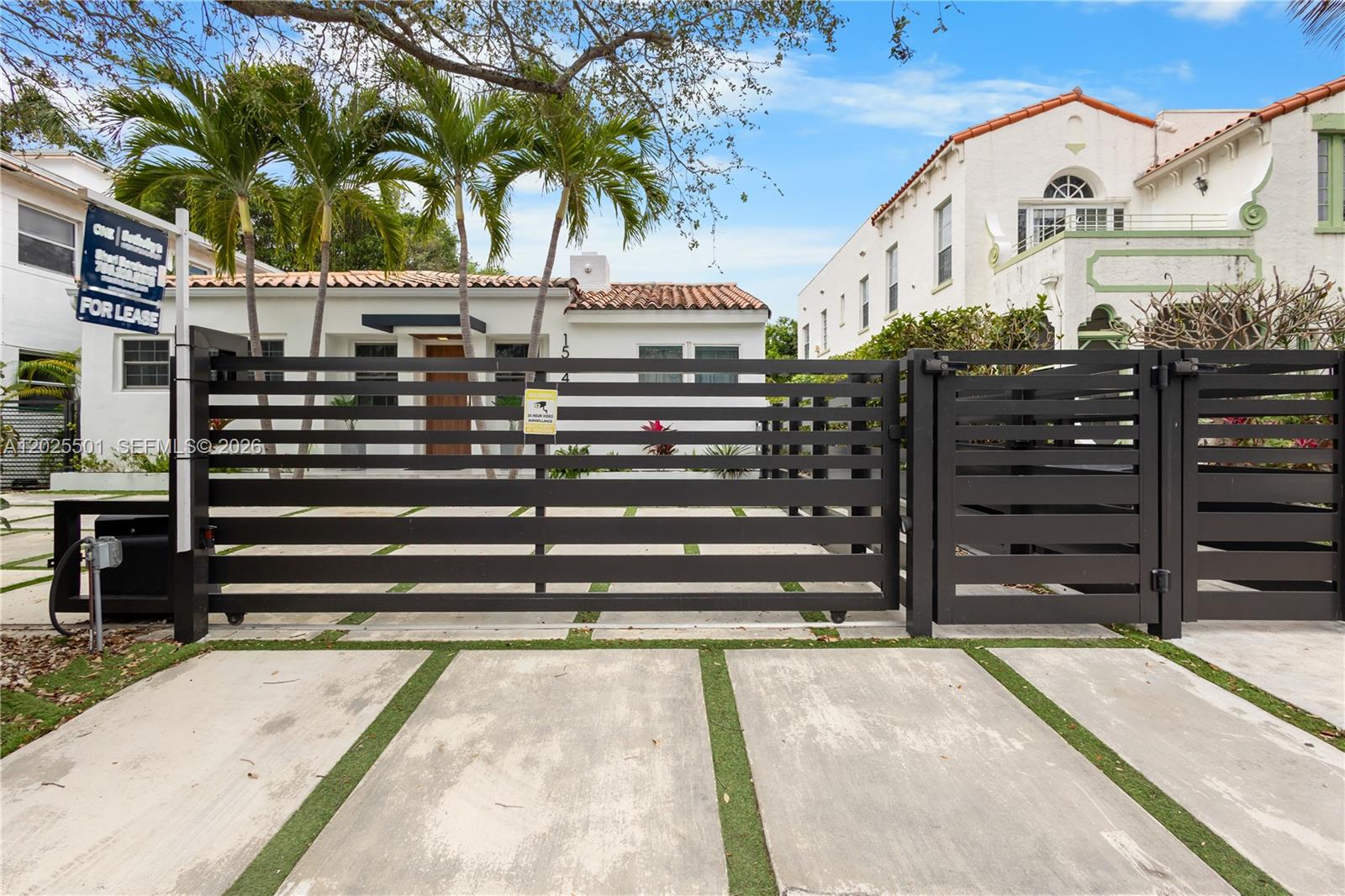 A white house with a tile roof is viewed through a modern black metal gate — 1544 Michigan Ave, Miami Beach FL 33139, MIAMI BEACH, FL