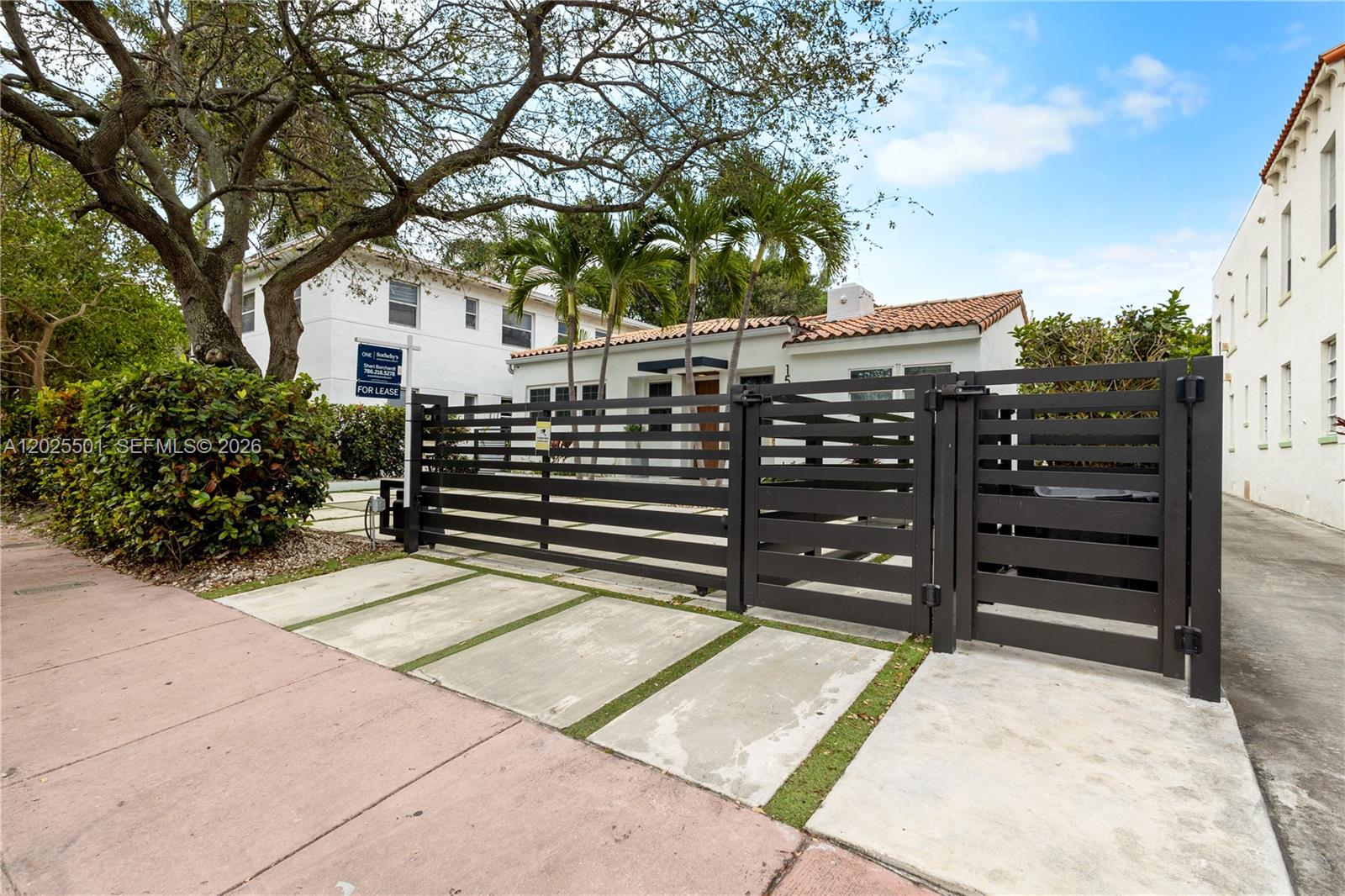 A white house with a tile roof is enclosed by a modern black horizontal fence — 1544 Michigan Ave, Miami Beach FL 33139, MIAMI BEACH, FL