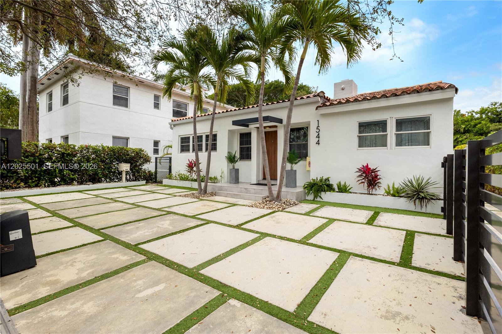A white single-story house features a paved driveway with grass strips and palm trees — 1544 Michigan Ave, Miami Beach FL 33139, MIAMI BEACH, FL