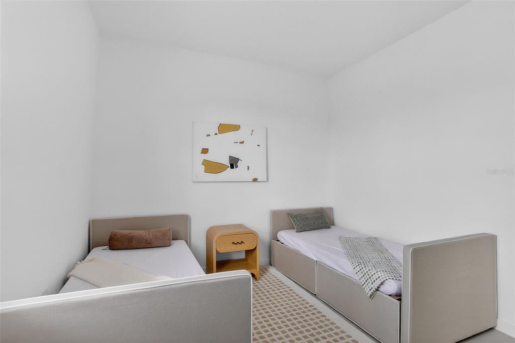 A bedroom features two twin beds with gray upholstered frames and a central wooden nightstand — 5579 MILLENIA PARK BOULEVARD UNIT 519, ORLANDO, FL