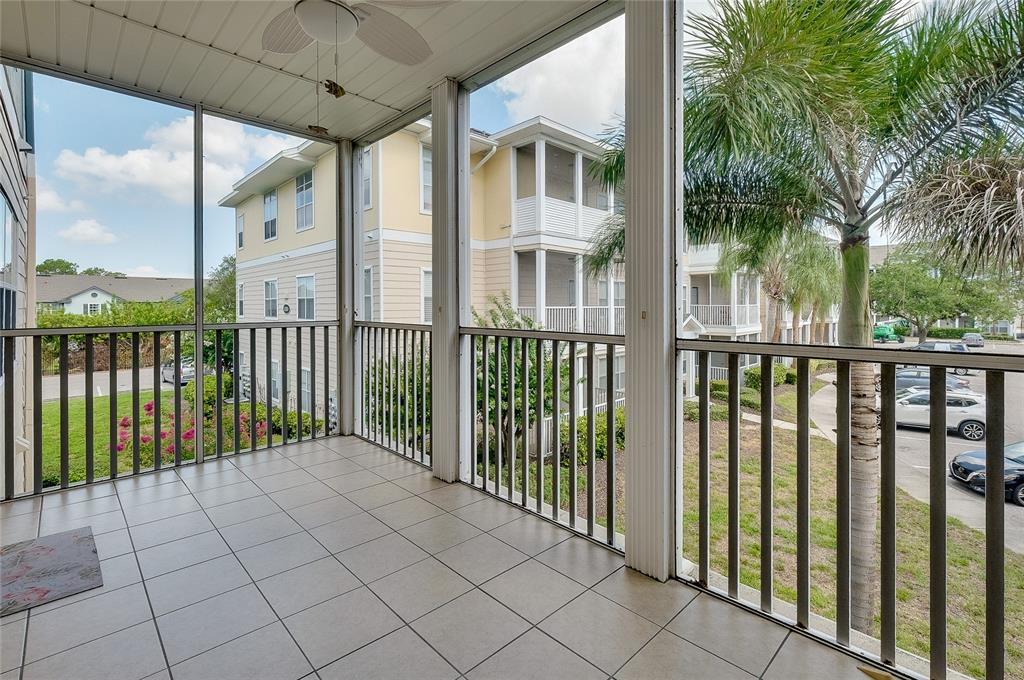 A screened-in balcony with tiled flooring overlooks a parking area and neighboring apartment buildings — 4802 51ST STREET W UNIT 1410, BRADENTON, FL