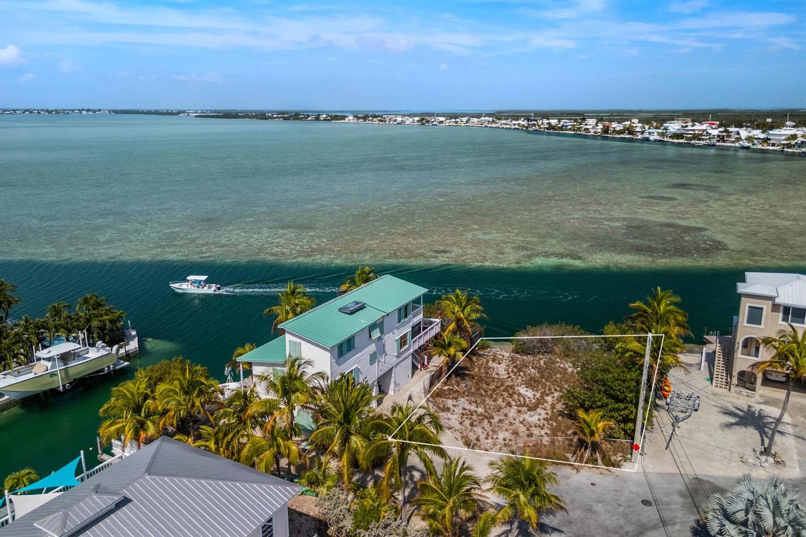 An aerial view shows a vacant waterfront lot next to a house with a boat — 00000 Lagoon Drive, FL 33042, FL