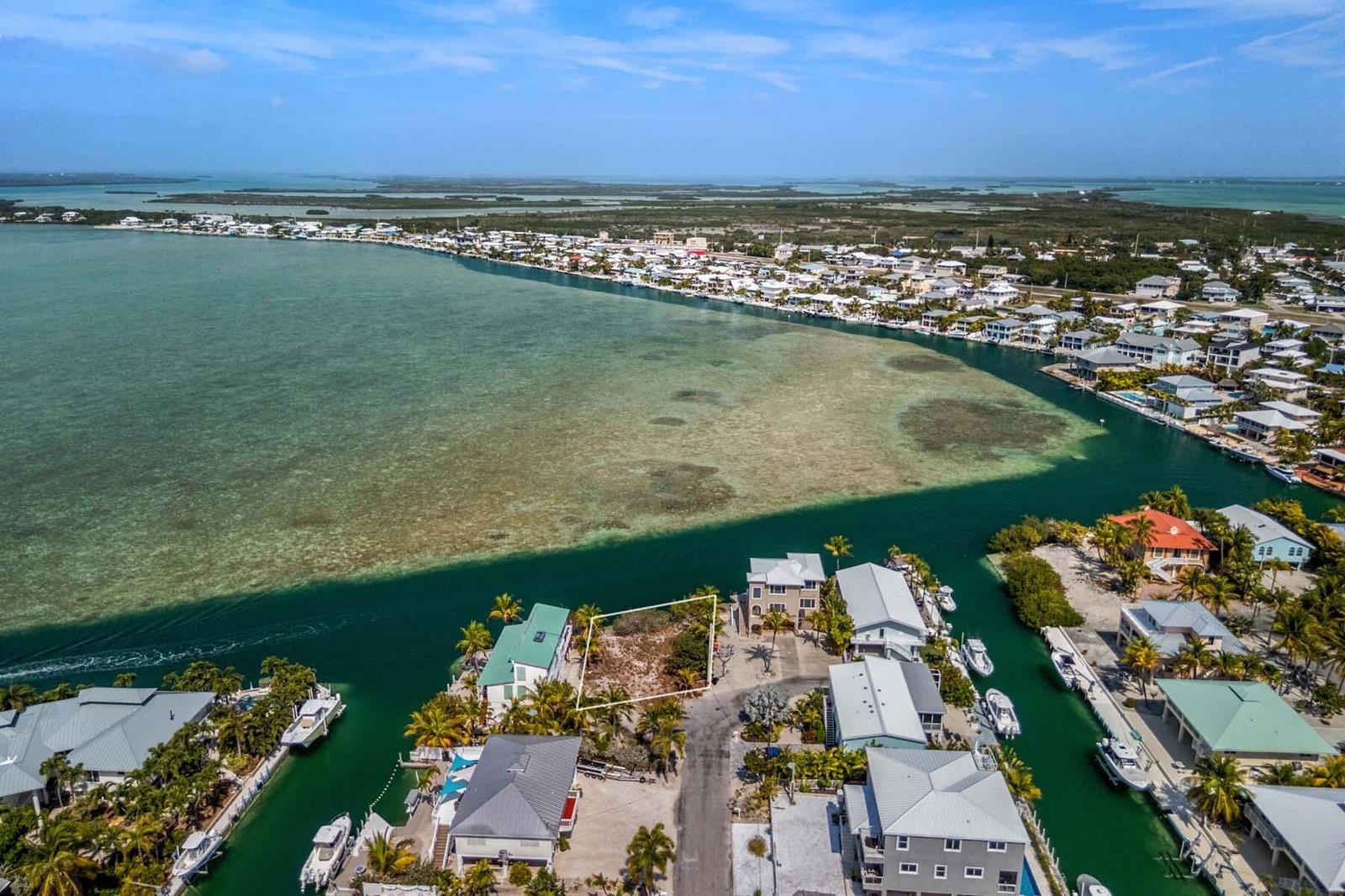 An aerial view shows a vacant waterfront lot outlined in white between two residential houses — 00000 Lagoon Drive, FL 33042, FL
