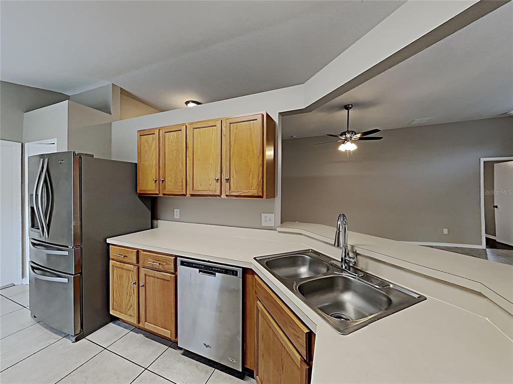 A kitchen features wood cabinets, stainless steel appliances, and a double-basin sink on a counter — 10328 SOARING EAGLE DRIVE, RIVERVIEW, FL