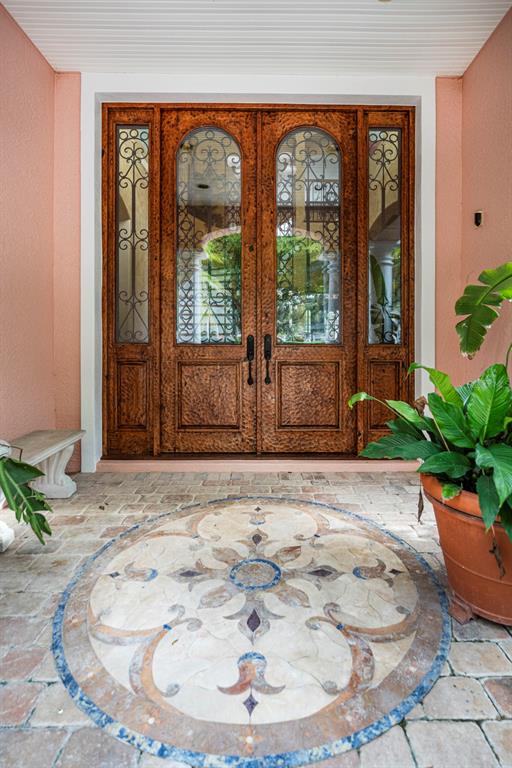 A double wooden front door with glass inserts sits above a decorative stone floor medallion — 543 ISLEWORTH CLOSE, TARPON SPRINGS, FL