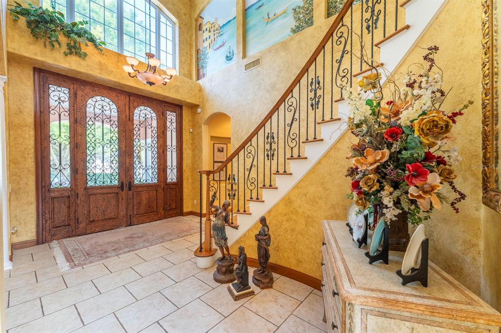 A grand foyer features a tiled floor, a wooden staircase, and a large arched doorway — 543 ISLEWORTH CLOSE, TARPON SPRINGS, FL