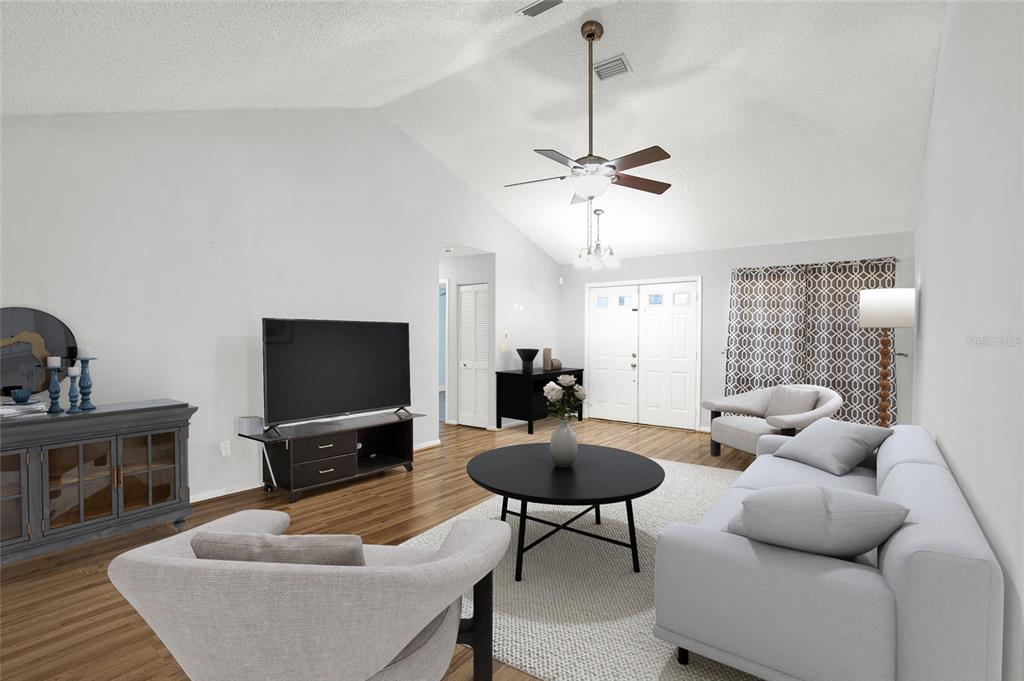 A living room features a vaulted ceiling, light wood flooring, and a neutral color palette — 9 BLACKBERRY PLACE, PALM COAST, FL