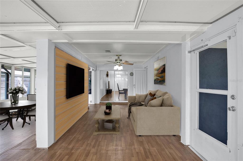 A living room features wood-look flooring, a wall-mounted television, a beige sofa, and a ceiling fan — 9 BLACKBERRY PLACE, PALM COAST, FL