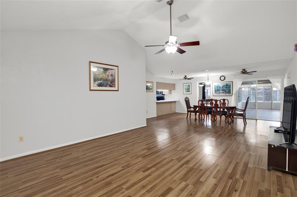 A spacious living and dining area features vaulted ceilings, wood-look flooring, and a ceiling fan — 9 BLACKBERRY PLACE, PALM COAST, FL