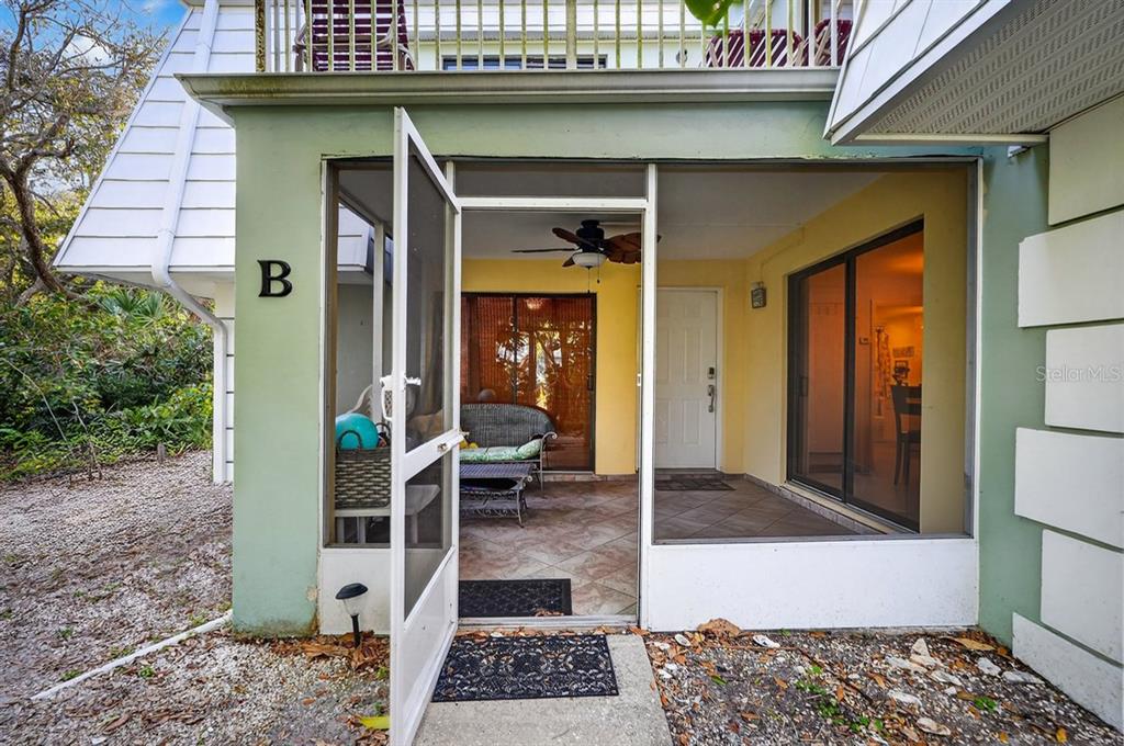 A screened-in patio with tile flooring, a ceiling fan, and a white entry door — 4150 S ATLANTIC AVENUE UNIT 114B, NEW SMYRNA BEACH, FL