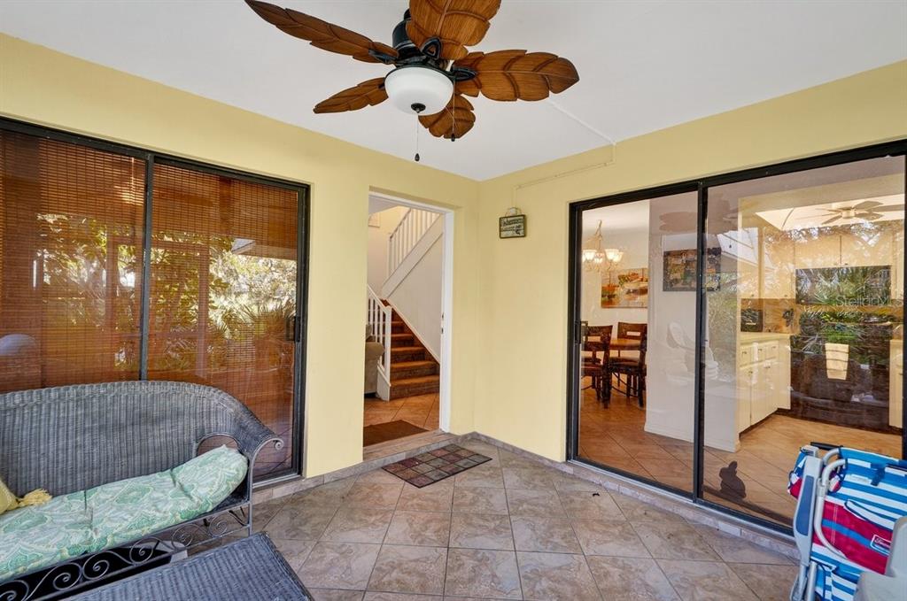 A covered patio with tile flooring, a leaf-shaped ceiling fan, and sliding glass doors — 4150 S ATLANTIC AVENUE UNIT 114B, NEW SMYRNA BEACH, FL