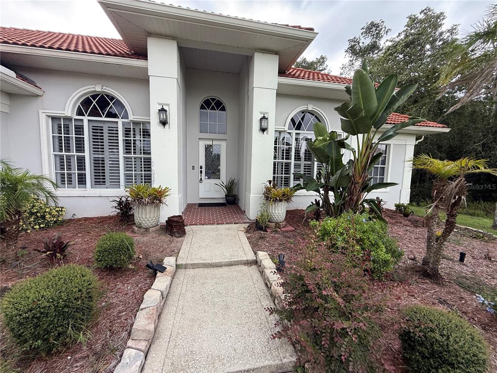 The exterior of a single-story house features a white facade, arched windows, and tiled roof — 325 LESLIE LANE, LAKE MARY, FL