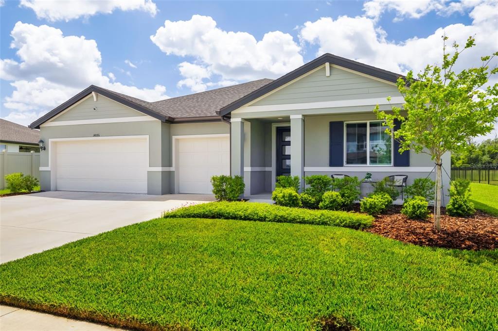 A single-story house with a two-car garage, light green siding, and a manicured front lawn — 14086 GINNIE SPRINGS WAY, PARRISH, FL