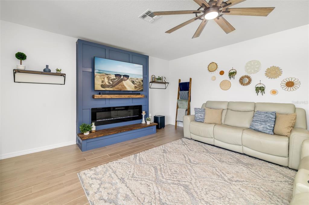 A living room features a blue accent wall with a fireplace, television, and light flooring — 14086 GINNIE SPRINGS WAY, PARRISH, FL