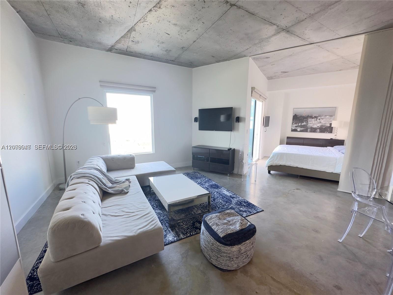 A studio apartment features a concrete ceiling, white walls, a sofa, and a bed — 10 SW South River Dr # 1607, Miami FL 33130, MIAMI, FL
