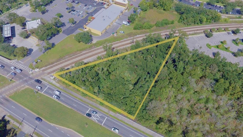 An aerial view shows a triangular, wooded vacant lot bordered by a road and railroad tracks — 2300 W LAKE MARY BOULEVARD, LAKE MARY, FL
