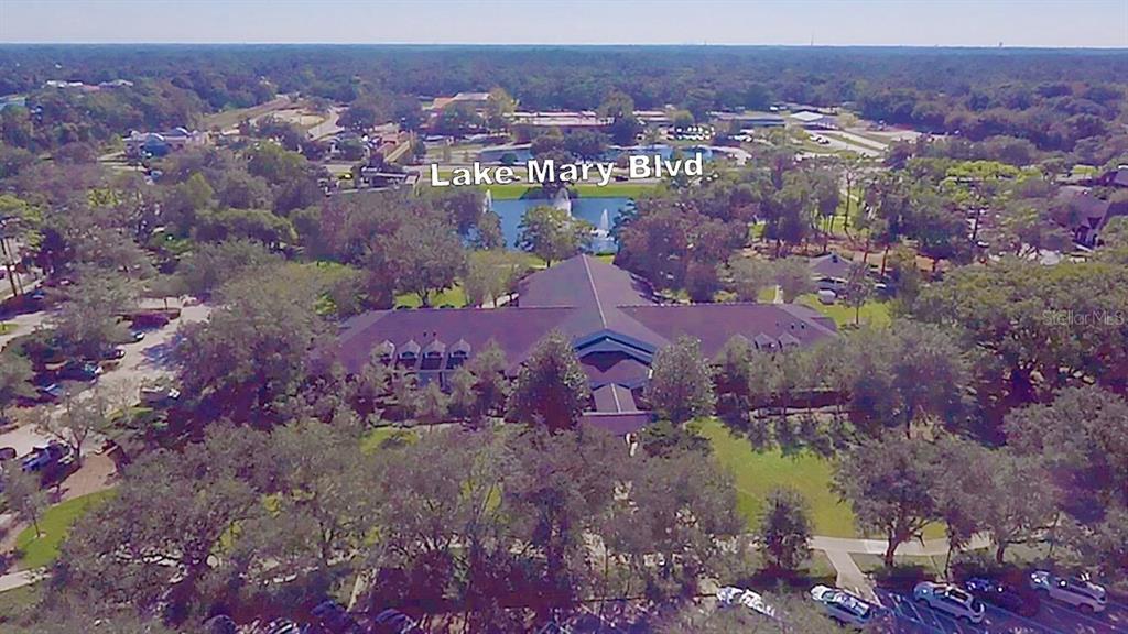 An aerial view shows a large building with a dark roof surrounded by trees — 2300 W LAKE MARY BOULEVARD, LAKE MARY, FL