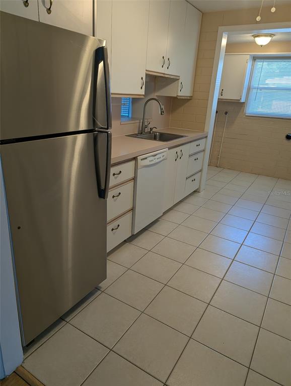 A kitchen features white cabinets, stainless steel appliances, a tile floor, and a sink — 314 ROSLYN AVENUE, NEW SMYRNA BEACH, FL