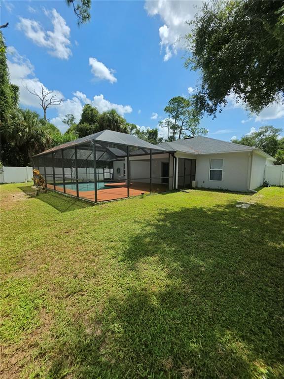 A backyard features a screened-in pool enclosure attached to the rear of a house — 3369 JENNINGS STREET, NORTH PORT, FL