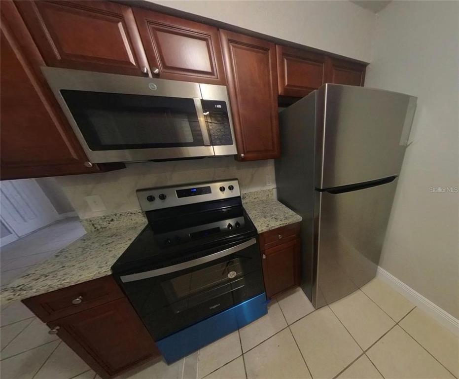 A kitchen features dark wood cabinets, stainless steel appliances, and granite countertops — 210 N LONE OAK DRIVE UNIT 1, LEESBURG, FL