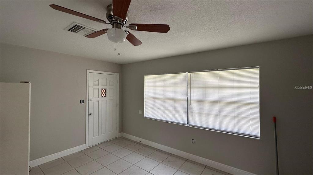 A room with tiled floors, a ceiling fan, a white door, and large windows — 210 N LONE OAK DRIVE UNIT 1, LEESBURG, FL