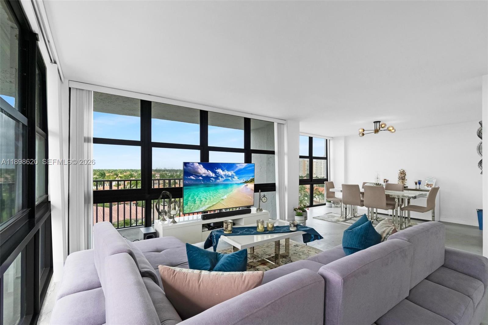 A living room features a large sectional sofa, a television, and a dining area — 1000 Parkview Dr # 809, Hallandale Beach FL 33009, HALLANDALE BEACH, FL