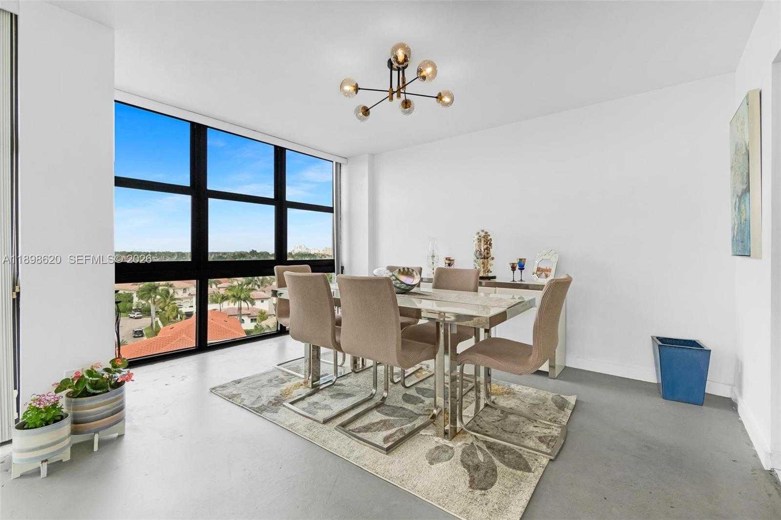 A dining room features a glass table, six chairs, a chandelier, and floor-to-ceiling windows — 1000 Parkview Dr # 809, Hallandale Beach FL 33009, HALLANDALE BEACH, FL