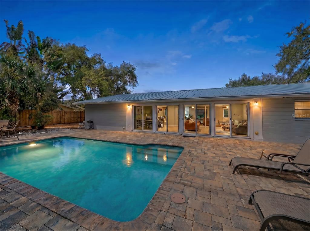 A backyard swimming pool with a stone patio and sliding glass doors to the house — 611 VENICE LANE, SARASOTA, FL