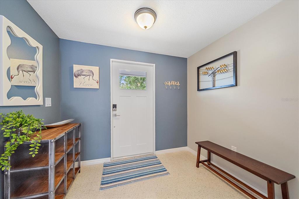 An entryway features a white door, blue and beige walls, a wooden bench, and shelving — 611 VENICE LANE, SARASOTA, FL