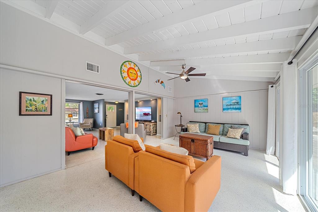 A bright living room features orange armchairs, a sofa, white beamed ceilings, and terrazzo flooring — 611 VENICE LANE, SARASOTA, FL