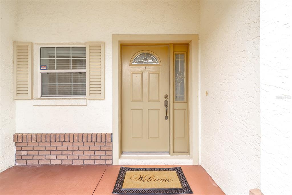 A beige front door with a side light and a window with shutters — 8722 SW 83RD LOOP, OCALA, FL