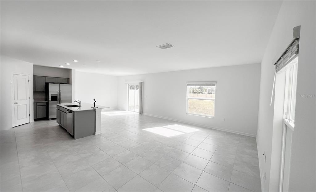 An open-concept kitchen and living area features gray cabinetry, a central island, and tile flooring — 1658 TEAGAN LANE, WINTER HAVEN, FL