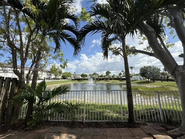 A view of a pond with a fountain behind a white metal fence and palm trees — 11419 NW 76th Ter, Doral FL 33178, DORAL, FL