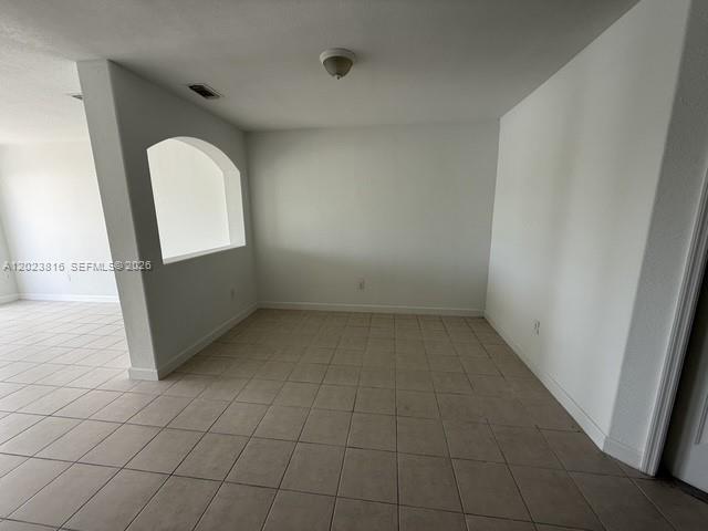 An empty room features white walls, a tiled floor, and a large arched wall cutout — 11419 NW 76th Ter, Doral FL 33178, DORAL, FL
