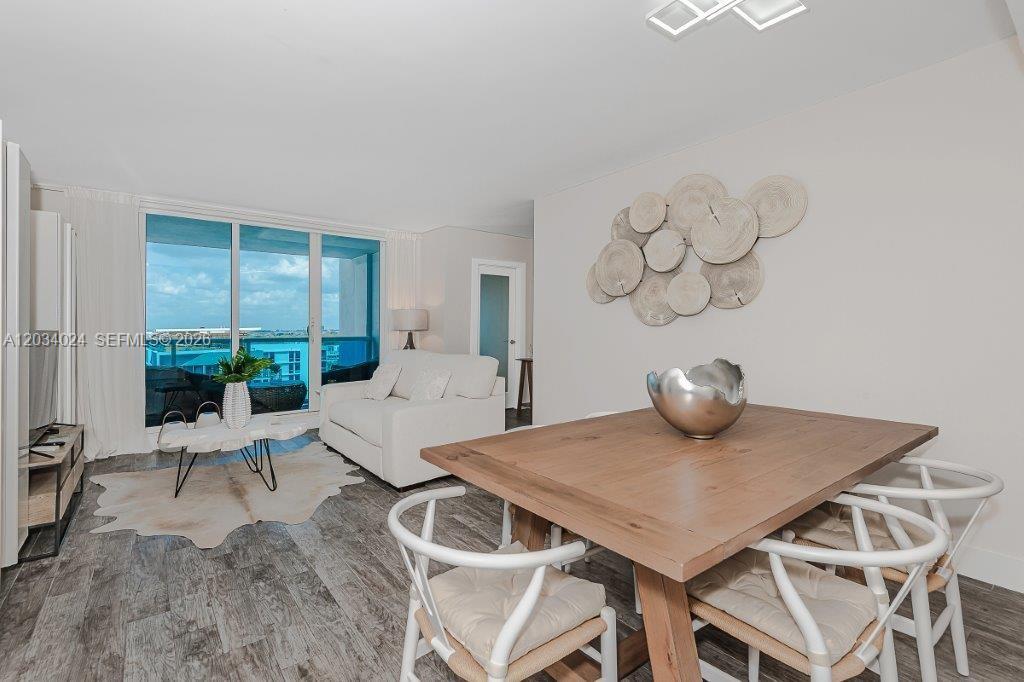 A dining area with a wooden table and white chairs sits beside a living space — 2301 Collins Ave # 926, Miami Beach FL 33139, MIAMI BEACH, FL