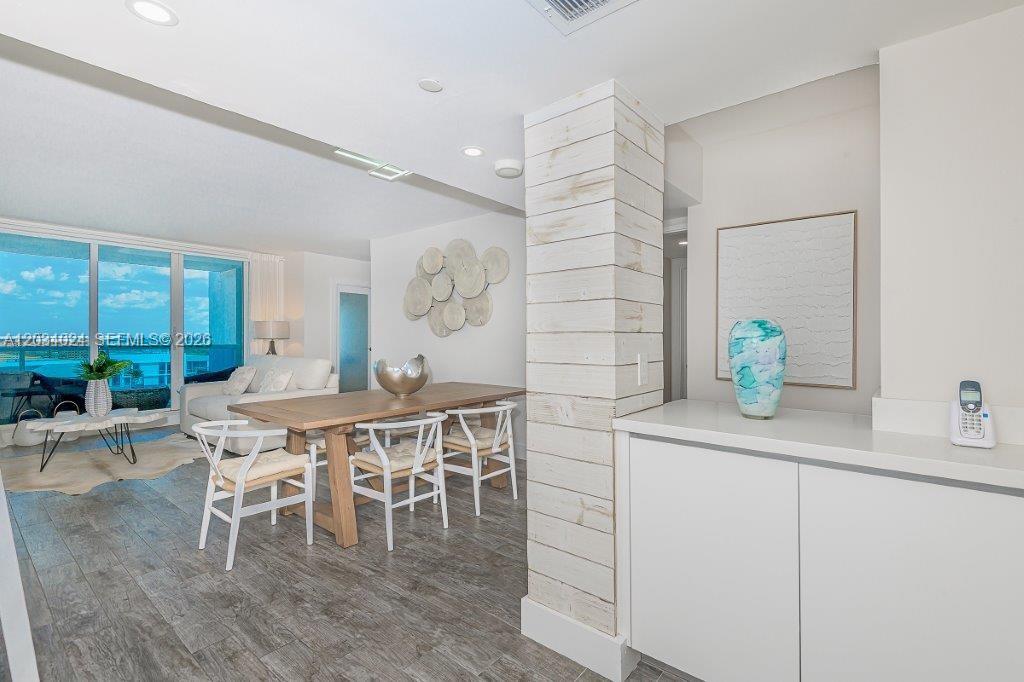 A dining area features a wooden table, white chairs, and a rustic wood-paneled pillar — 2301 Collins Ave # 926, Miami Beach FL 33139, MIAMI BEACH, FL
