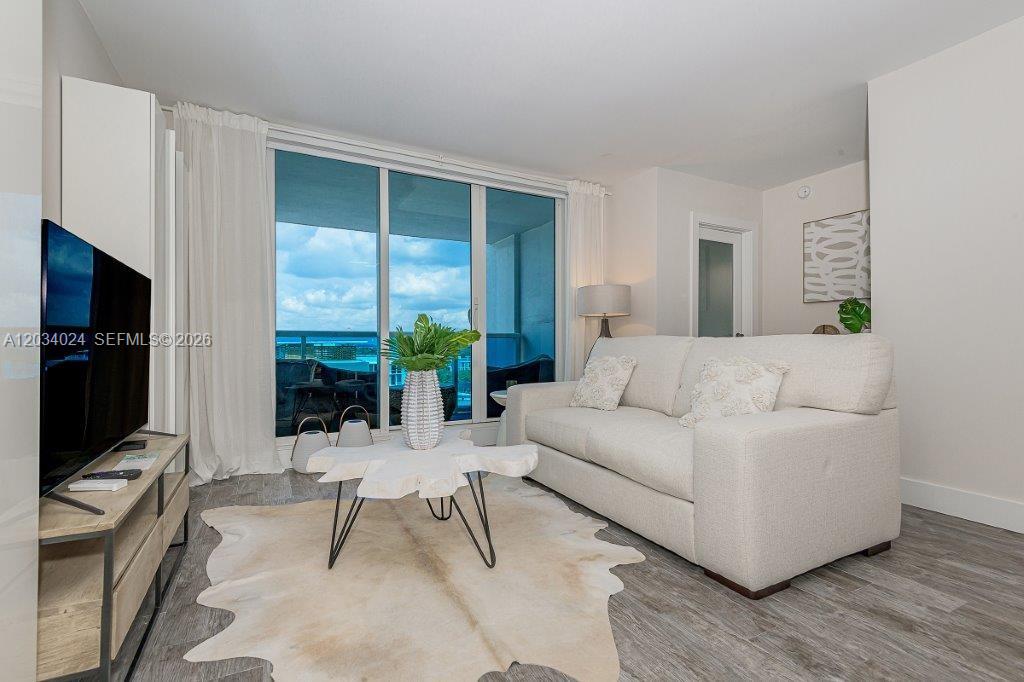 A living room features a white sofa, a wood-slice coffee table, and a balcony view — 2301 Collins Ave # 926, Miami Beach FL 33139, MIAMI BEACH, FL