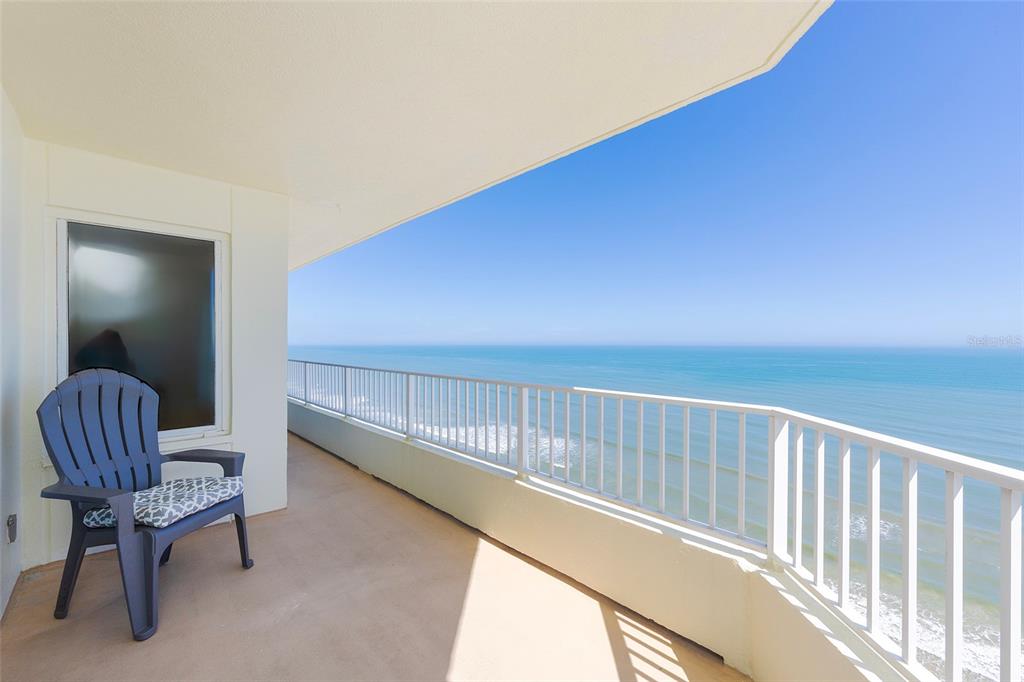 A balcony with a blue chair overlooks the ocean under a clear blue sky — 2937 S ATLANTIC AVENUE UNIT 1606, DAYTONA BEACH SHORES, FL