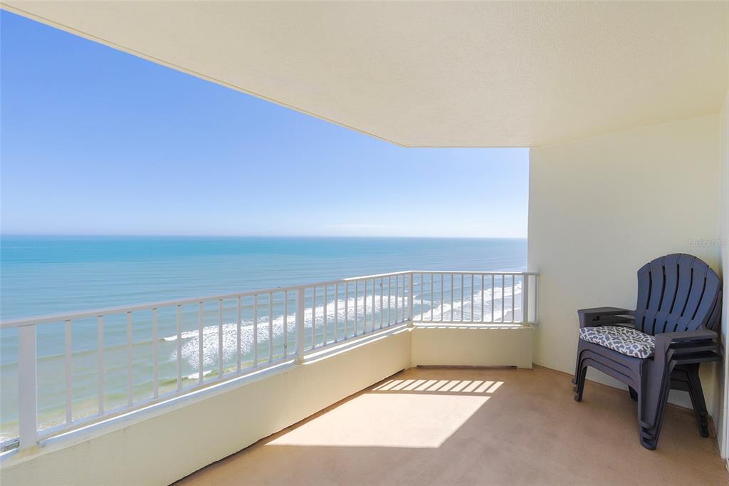 A balcony with a white railing overlooks the ocean and features a stack of chairs — 2937 S ATLANTIC AVENUE UNIT 1606, DAYTONA BEACH SHORES, FL