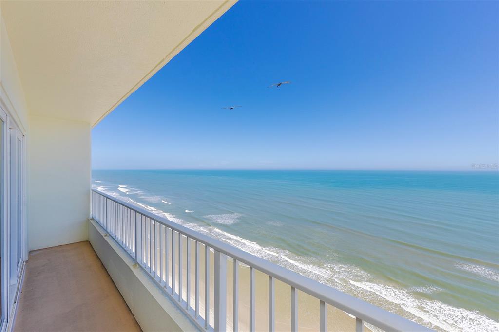 A high-rise balcony overlooks the ocean with a white railing and clear blue sky — 2937 S ATLANTIC AVENUE UNIT 1606, DAYTONA BEACH SHORES, FL