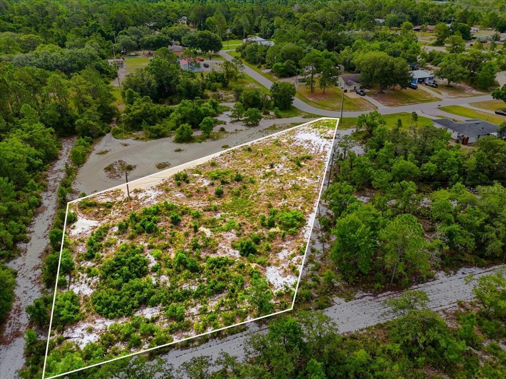 An aerial view shows a vacant, irregularly shaped lot surrounded by trees and paved roads — 2000 LEMON DRIVE, LAKE WALES, FL