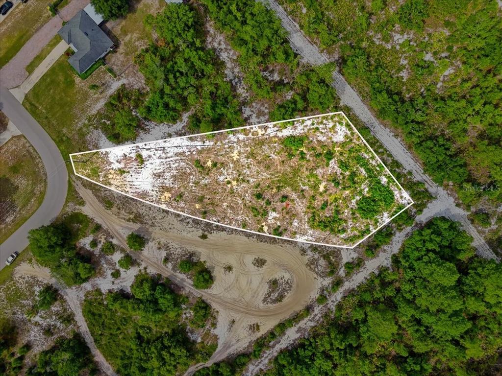 An aerial view shows a vacant, irregularly shaped lot surrounded by trees and dirt roads — 2000 LEMON DRIVE, LAKE WALES, FL
