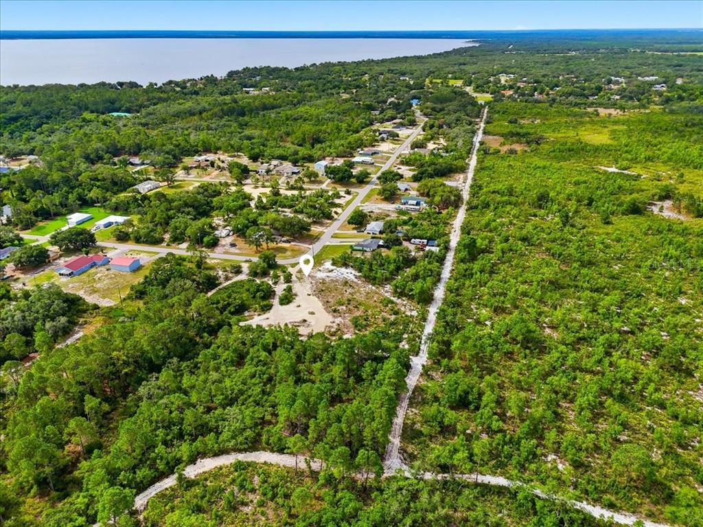 An aerial view shows a vacant, sandy lot surrounded by trees near a residential street — 2000 LEMON DRIVE, LAKE WALES, FL