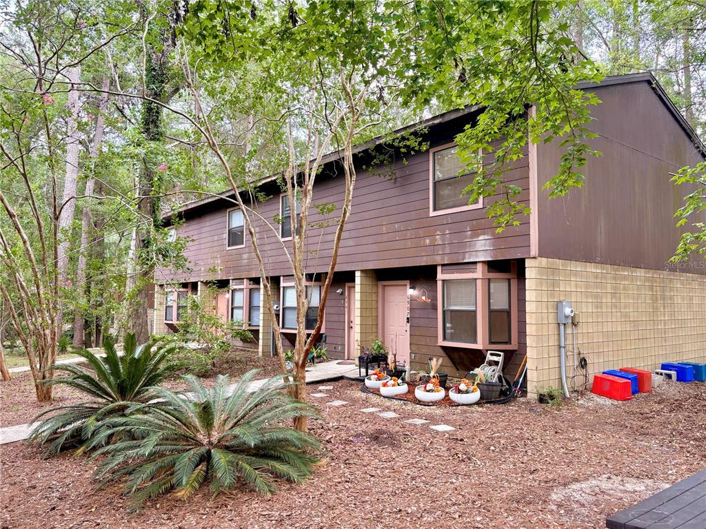 A two-story brown townhouse with a block foundation, bay windows, and a landscaped front yard — 6907 SW 44TH AVENUE, GAINESVILLE, FL