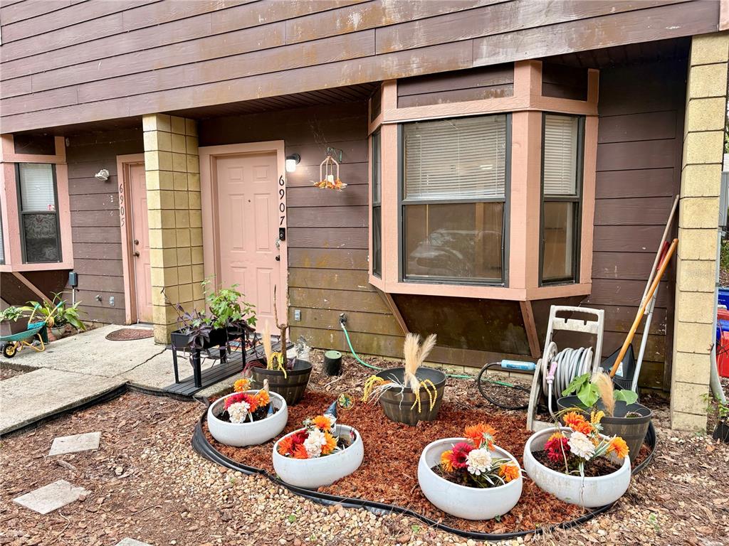The exterior of a brown multi-unit building features two pink doors and a bay window — 6907 SW 44TH AVENUE, GAINESVILLE, FL
