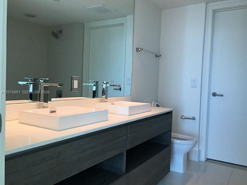 A modern bathroom features a double vanity with vessel sinks and a dark wood cabinet — 1100 S MIAMI AV # 3302, Miami FL 33130, MIAMI, FL