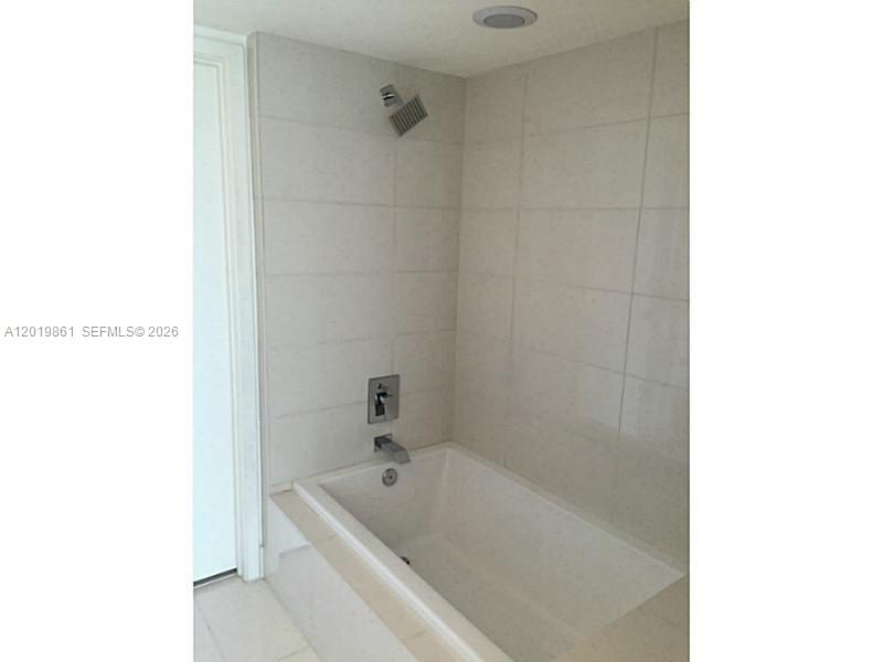 A white bathtub with a wall-mounted shower head and light-colored tile surround — 1100 S MIAMI AV # 3302, Miami FL 33130, MIAMI, FL