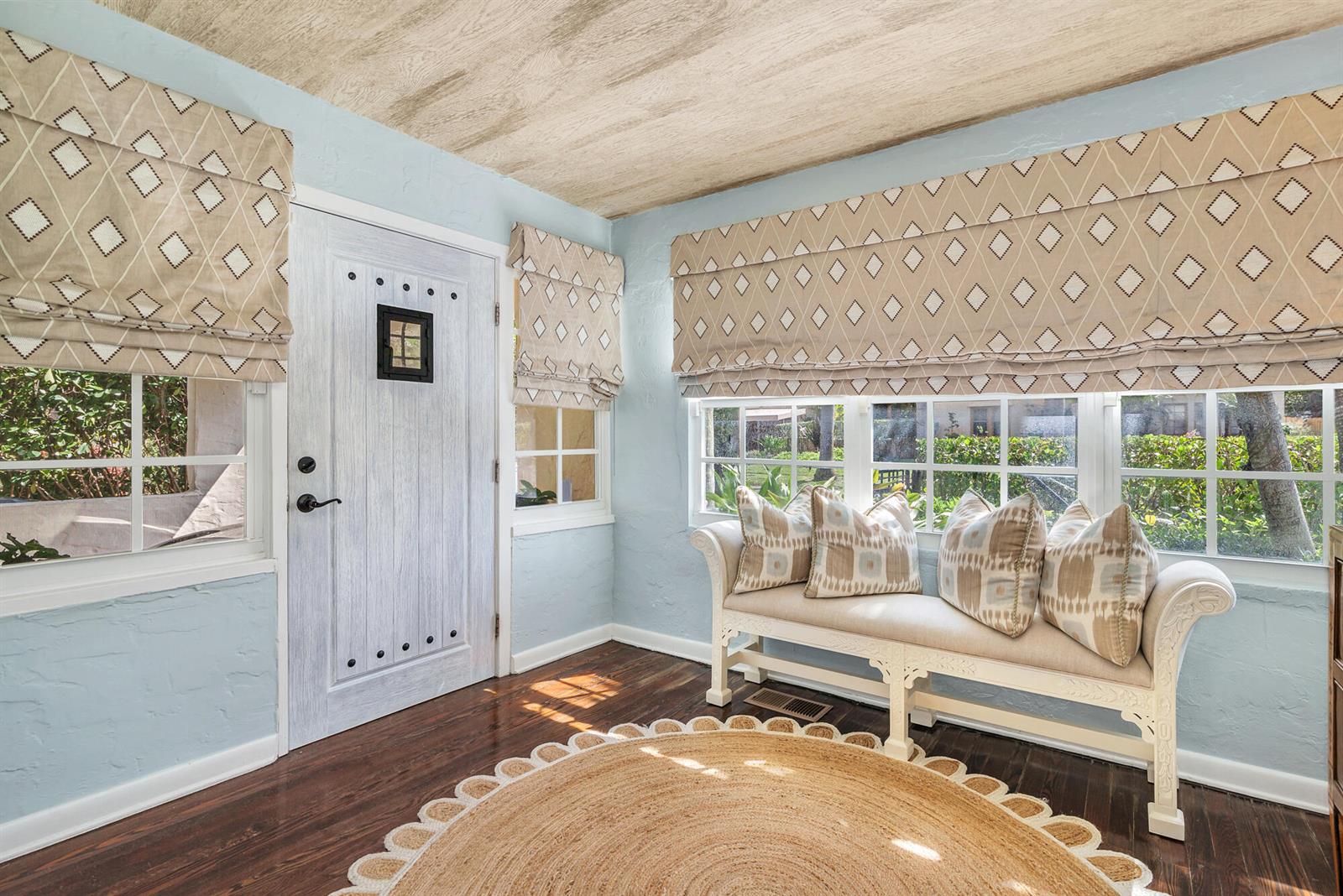 A light blue entryway features a white door, a window bench, and a round rug — 3213 Vincent Road, West Palm Beach FL 33405, WEST PALM BEACH, FL
