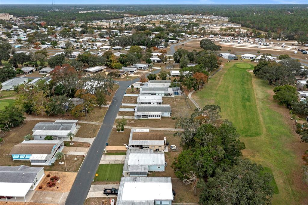 An aerial view shows a residential neighborhood with mobile homes bordering a grassy golf course — 12045 FORMOSA STREET, BROOKSVILLE, FL